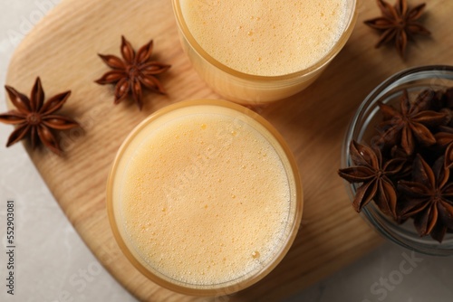 Glasses of delicious eggnog with anise on grey marble table, top view