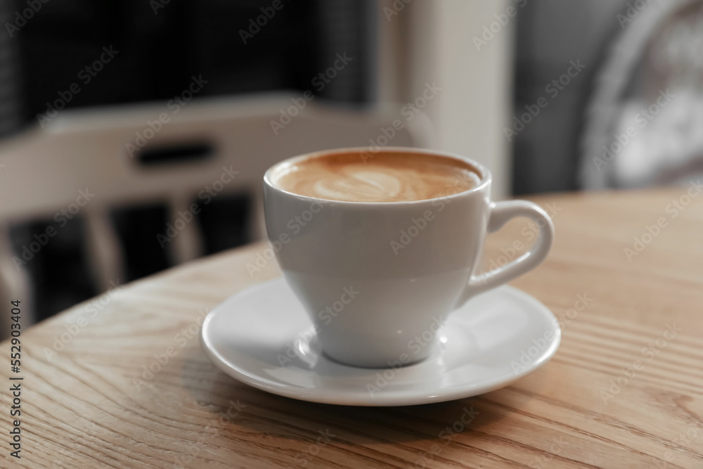 Cup of aromatic hot coffee on wooden table in cafe