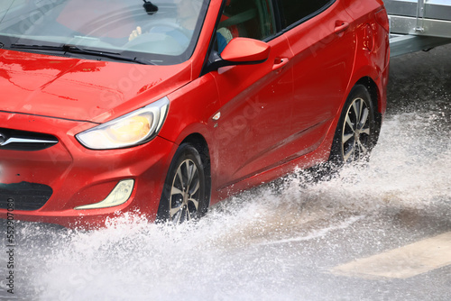 car is driving through a puddle splashes rain downpour