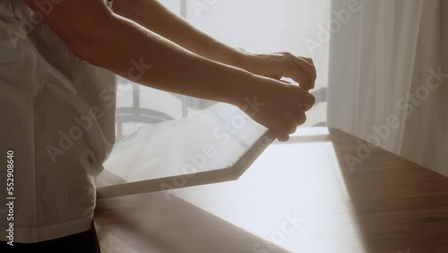 artist unpack small canvas from package. girl in white T-shirt is about to paint on blank sheet of paper in morning at dawn. Starting life with clean slate, starting all over again.