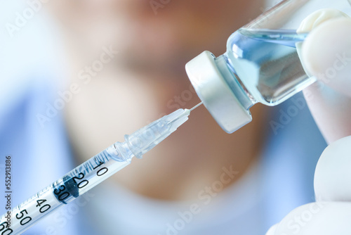 Φωτογραφία doctor's hand holds a syringe and a blue vaccine bottle at the hospital