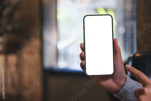 Mockup image of a woman holding and pointing finger at a mobile phone with blank white screen