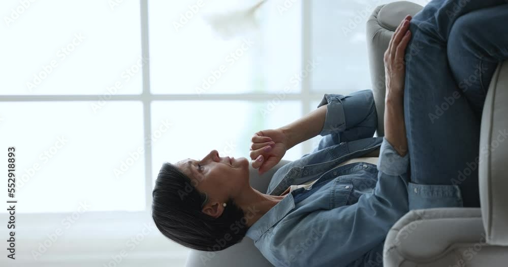 Pensive middle-aged woman sits on armchair in living room look out window, thinking or pondering. Lonely thoughtful older female resting at home feel alone lost in sad thoughts, mourning or yearning Pensive middle-aged woman sits on armchair in living room look out window, thinking or pondering. Lonely thoughtful older female resting at home feel alone lost in sad thoughts, mourning or yearning