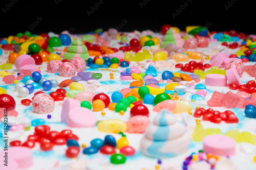 Multi-colored candy balls on icing sugar table. Candy sweets background made of assorted chocolate coated and jelly beans. Various shaped delicious sugary treats. Holiday festive background. Multi-colored candy balls on icing sugar table. Candy sweets background made of assorted chocolate coated and jelly beans. Various shaped delicious sugary treats. Holiday festive background.