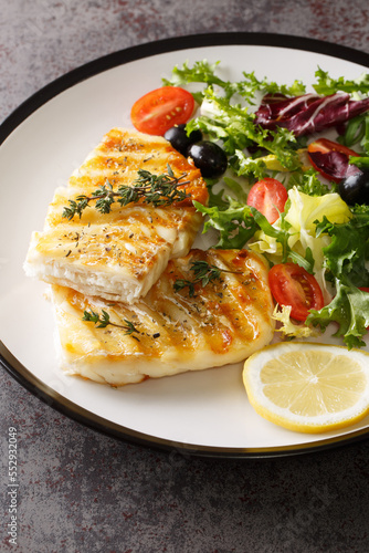 фотографія Grilled cod fillet served with fresh vegetable salad close-up in a plate on the table