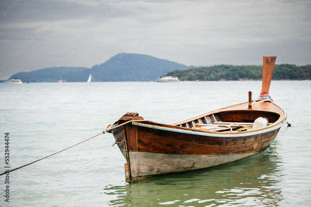 Traditional Thai boat LONGTAIL in the water at anchor without a motor, against the background of the sky and the island. Authentic landscape. Traditional Thai boat LONGTAIL in the water at anchor without a motor, against the background of the sky and the island. Authentic landscape.