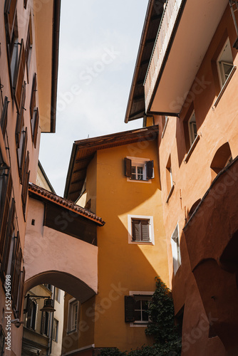 Historic architecture in Italy. Traditional European old town street buildings. Wooden windows, shutters and colourful walls with aesthetic sunlight shadows. Summer vacation travel background