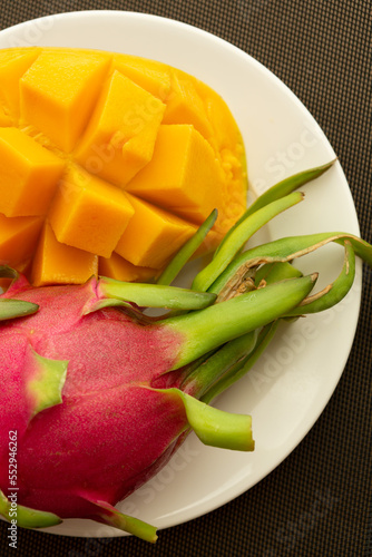 on a white dish lie mango, pitahaya close-up