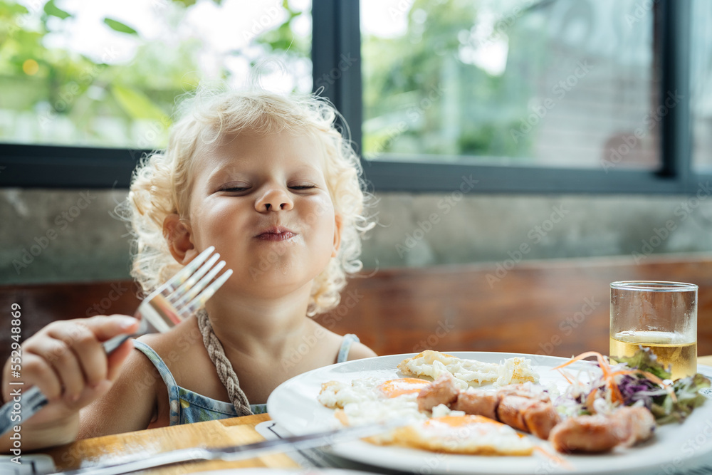 © galaganov - The child is happy to eat food from a plate with an emotion of joy and happiness. Very tasty and fun.