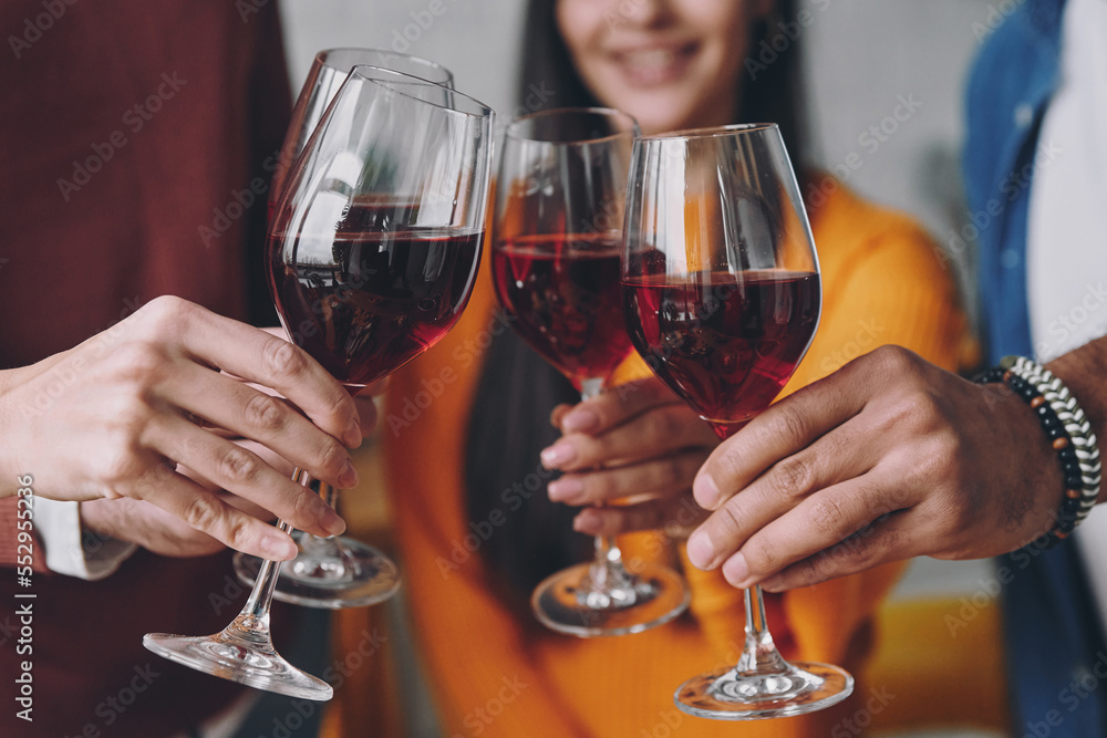 Close-up of young people toasting with wine while spending time together Close-up of young people toasting with wine while spending time together