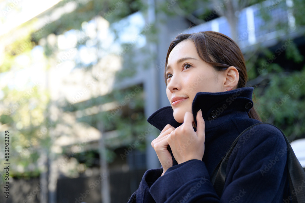 A woman tugging at the collar of her coat because it's winter and she's cold. A woman tugging at the collar of her coat because it's winter and she's cold.