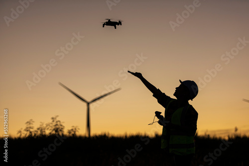 silhouette of a person with UAV. Silhouette person take off UAV. on hand on wind turbine on background