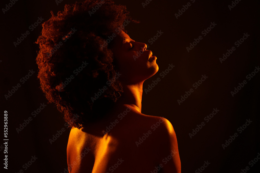 Nude African American female under orange light Nude African American female under orange light