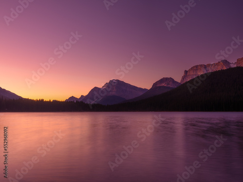Mountain landscape at dawn. Sunbeams in a valley. Lake and forest in a mountain valley at dawn. Natural landscape with bright sunshine. High rocky mountains. Banff National Park, Alberta, Canada. 