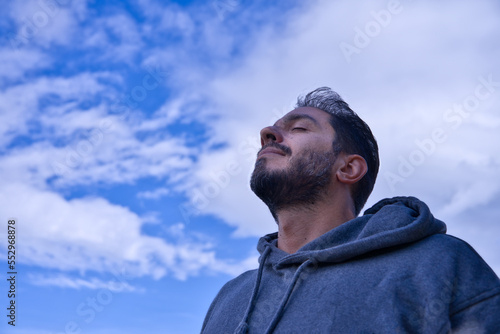Adult breathing fresh air outdoors against blue sky and clouds.