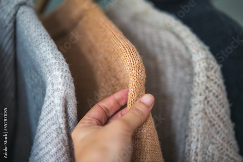 Obraz na płótnie Close-up female hand touching the fabric of a warm sweater, winter clothing quality concept w salonie