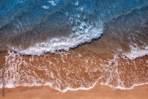 Turquoise water wave with sand beach background from aerial top view. Concept summer sunny travel image