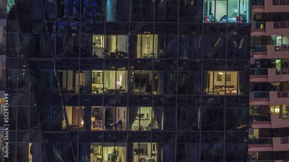Windows lights in modern office and residential buildings timelapse at night. Multi-level skyscrapers with illuminated rooms inside and reflections from glass surface Windows lights in modern office and residential buildings timelapse at night. Multi-level skyscrapers with illuminated rooms inside and reflections from glass surface