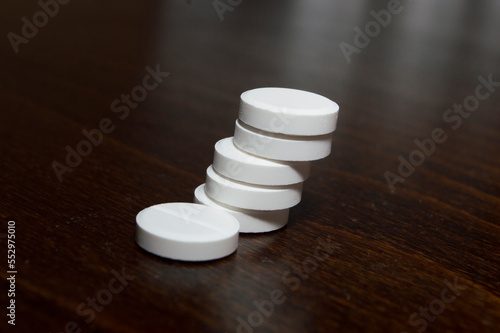 White round tablets on a wooden surface. A medicinal product.

