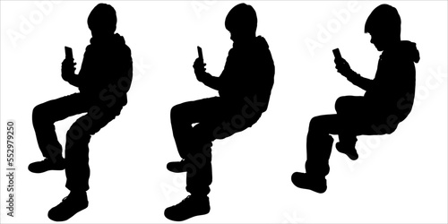 Teenagers and mobile phones. A teenager sits and holds his phone with one hand, looks at the screen. Side view. People use smartphones. Men with cellular devices. Black silhouettes isolated 
