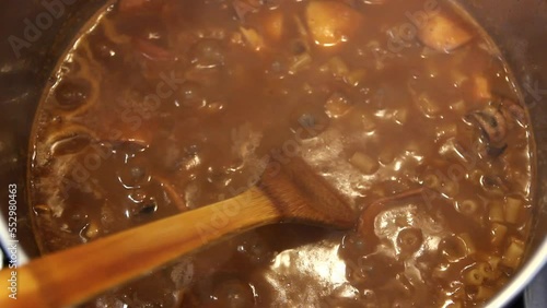 Boiling cuttlefish, pasta in tomato sauce in a pot. Closeup
