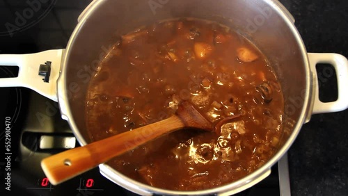 Simmering cuttlefish, pasta in tomato sauce in a pot. Closeup