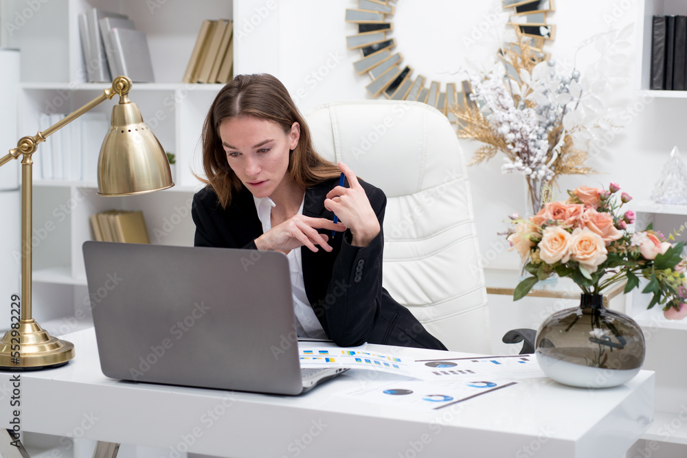 Young woman working with a laptop at her desk in the office Young woman working with a laptop at her desk in the office