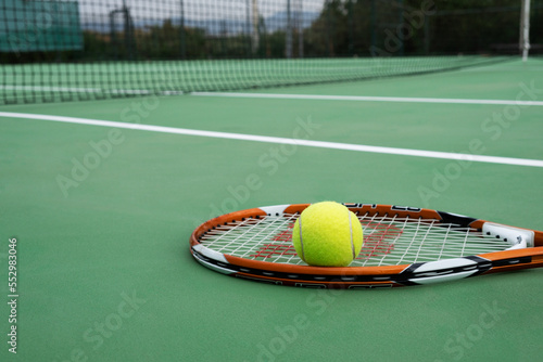 Tennis racket and ball, green court © doganyavas