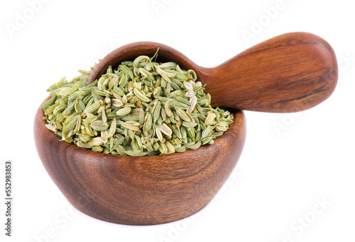 Fennel seeds in wooden bowl and spoon, isolated on white background. Green fennel grains. Spices and herbs.
