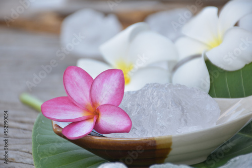 Soft focus of purple plumeria flower and white alum cube on ceramic pot and white plumeria flowers background  spa and skincare concept.