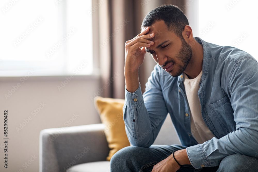 Portrait Of Depressed Young Black Man Sitting On Couch At Home Portrait Of Depressed Young Black Man Sitting On Couch At Home