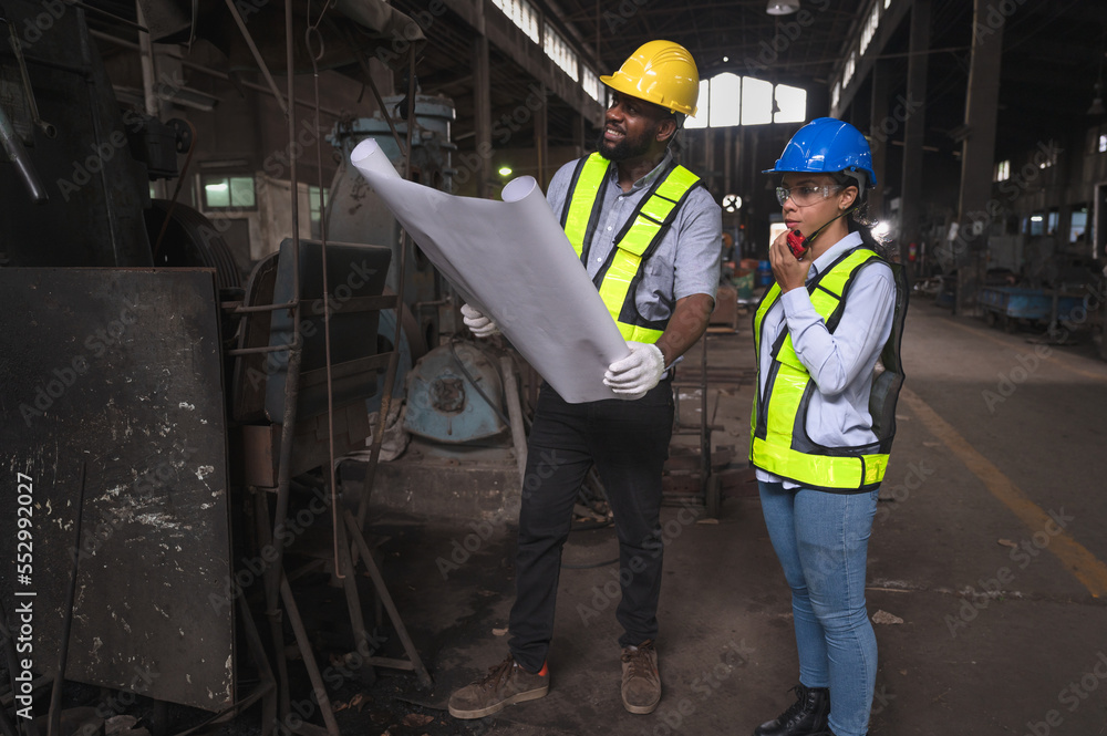Portrait labor engineer African American use paperwork and Latin America woman engineer holding walkie talkie at lathe factor Portrait labor engineer African American use paperwork and Latin America woman engineer holding walkie talkie at lathe factor