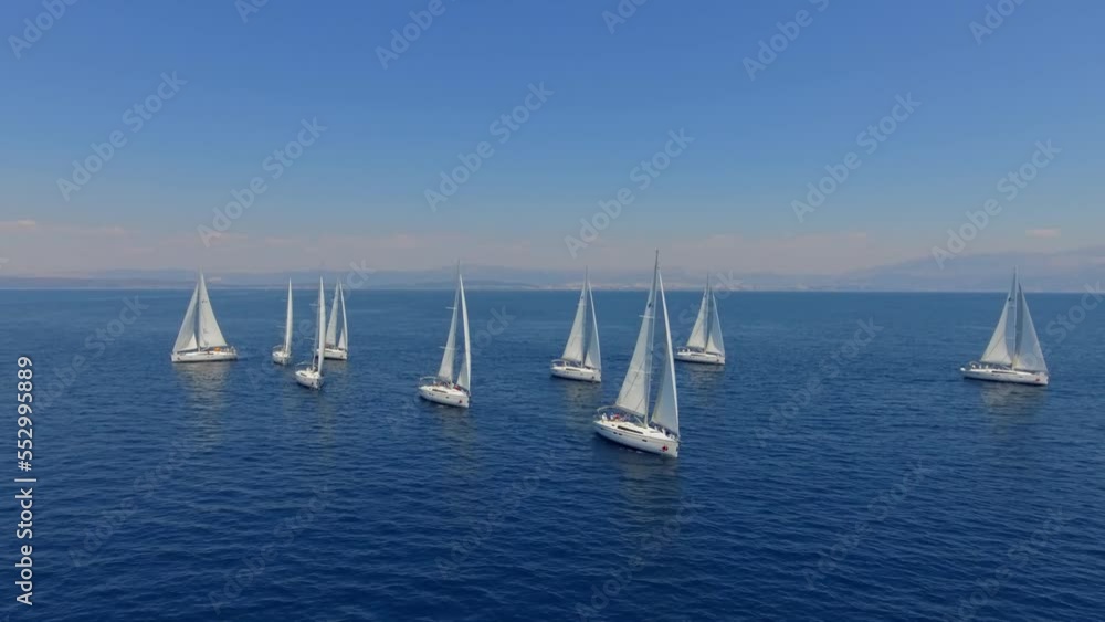 Aerial view flying over yachts competing with each other from the mediterranean sea in croatia on a bright sunny day against the backdrop of a picturesque green island. white yachts sail beautifully a Aerial view flying over yachts competing with each other from the mediterranean sea in croatia on a bright sunny day against the backdrop of a picturesque green island. white yachts sail beautifully a