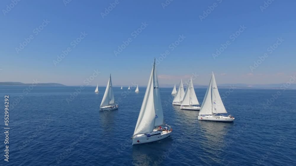 Aerial view flying over yachts competing with each other from the mediterranean sea in croatia on a bright sunny day against the backdrop of a picturesque green island. white yachts sail beautifully a Aerial view flying over yachts competing with each other from the mediterranean sea in croatia on a bright sunny day against the backdrop of a picturesque green island. white yachts sail beautifully a