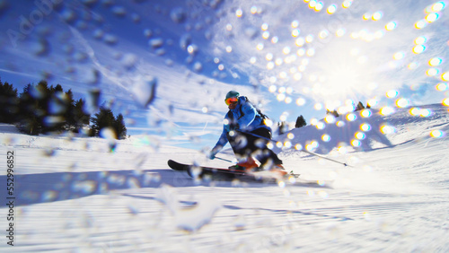 Professional skier skiing on slopes in the Swiss alps and throwing snow at the camera. Water drops visible.