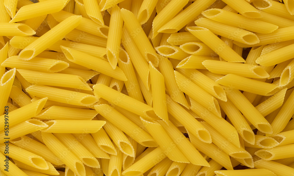 Uncooked penne pasta. Top view of bright background image. Uncooked penne pasta. Top view of bright background image.