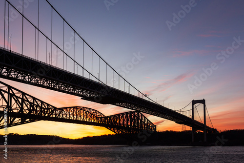 Low angle view of the 1970 suspension Pierre-Laporte Bridge and 1919 steel truss Quebec Bridge over the St. Lawrence River seen during sunrise, Quebec City, Quebec, Canada
