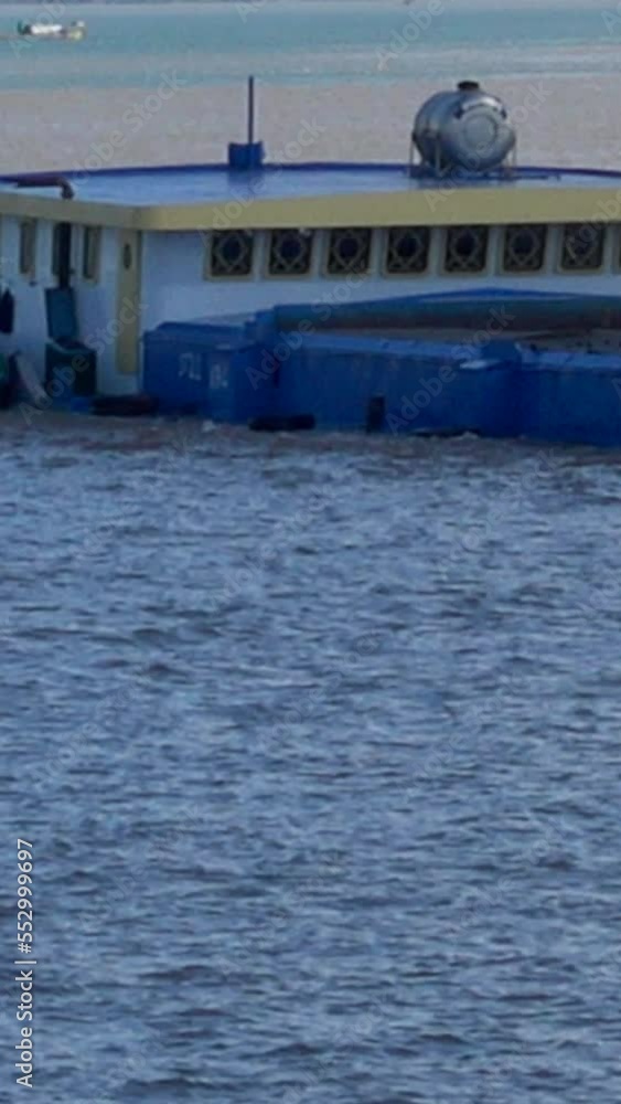 Vertical video of A peniche boat with heavy load on the Mekong river in Phnom Penh. The boat is so low on the water it looks like it's half under and is sinking. Vertical video of A peniche boat with heavy load on the Mekong river in Phnom Penh. The boat is so low on the water it looks like it's half under and is sinking.