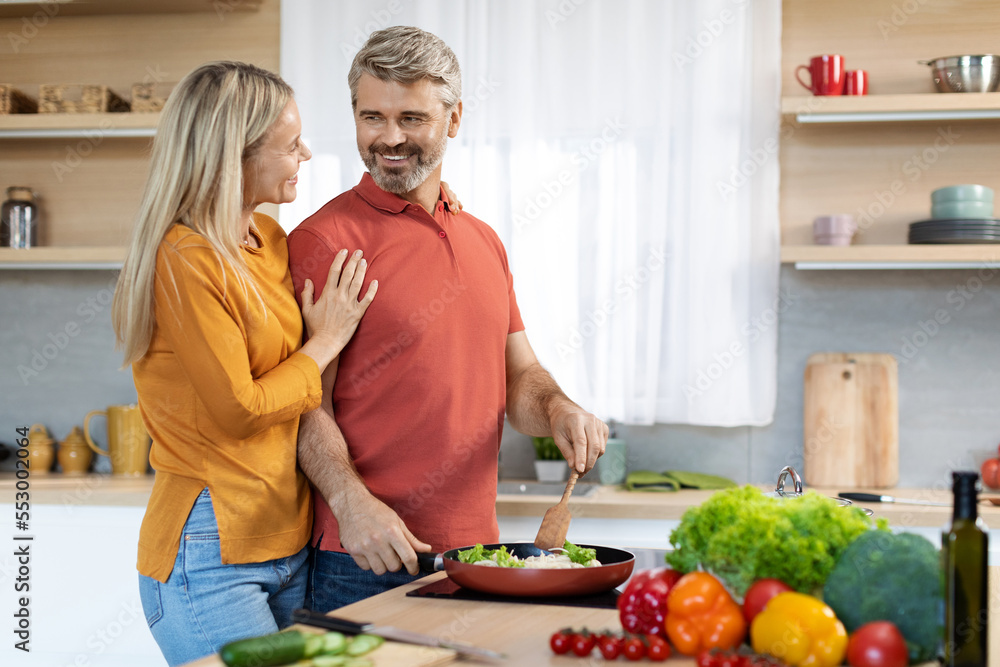 Loving wife hugging her handsome husband while cooking at home Loving wife hugging her handsome husband while cooking at home