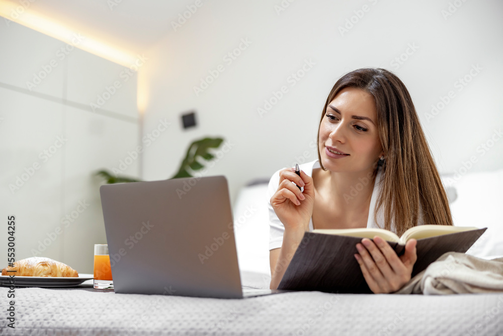 Fototapeta premium Woman using laptop in bedroom