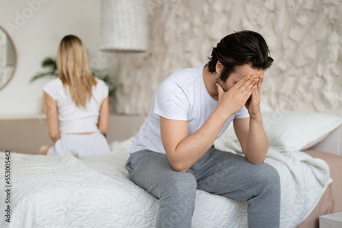 Relationship crisis. Caucasian man feeling upset after fight with his wife, sitting back to back on bed at home