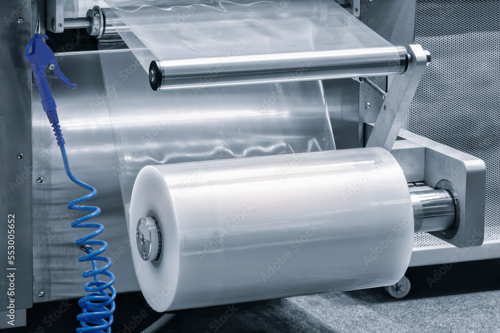 Automatic polyethylene plastic bag production machine with lighting effect. Close-up of the roller of the plastic bag production machine in the light blue scene. product packaging concept Automatic polyethylene plastic bag production machine with lighting effect. Close-up of the roller of the plastic bag production machine in the light blue scene. product packaging concept