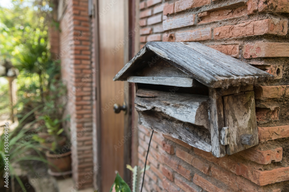 Old wooden mailbox by brick house front door
