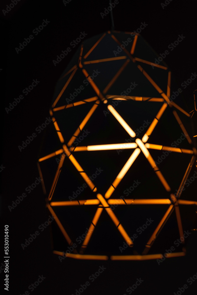 Black lamps with a geometric pattern, three lamps on a black background, burning with warm light, with a graphic pattern Black lamps with a geometric pattern, three lamps on a black background, burning with warm light, with a graphic pattern