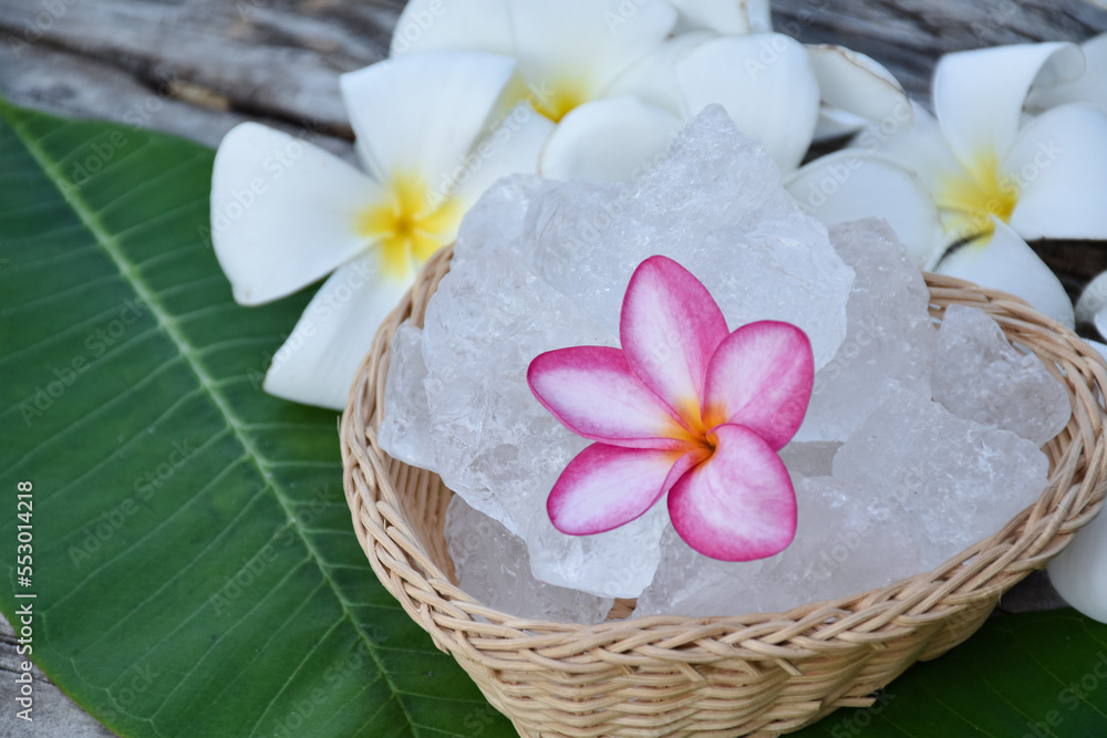 Soft focus of purple plumeria flower and white alum cube on wicker basket, spa and skincare concept. Soft focus of purple plumeria flower and white alum cube on wicker basket, spa and skincare concept.