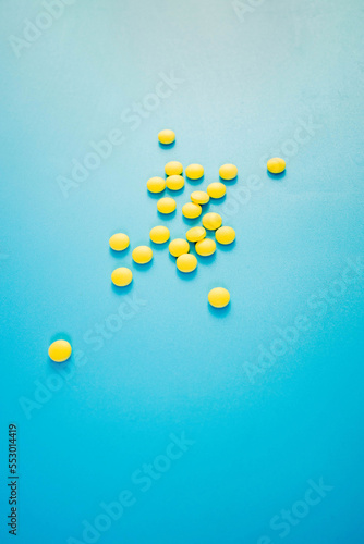 Chaotically arranged yellow pills on a blue background, healthy and medicine concept