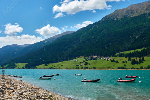 Lifeboats on the shore for personal rescue and training purposes. Watercraft in front of beautiful mountain landscape in the lake (Reschensee). Italy, Vinschgau, Giern.