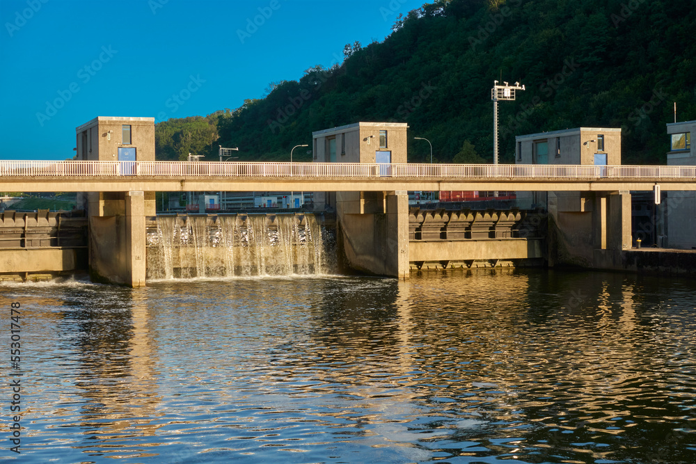 Concrete water building in a river. Dam to close a water body. Warm evening light in summer. Front view. Germany, Esslingen near Stuttgart.