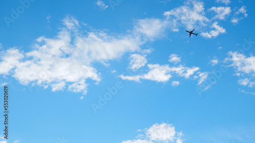 The passenger plane is flying far away in the blue sky and white clouds. Airplane in the air. International passenger air transportation. Wallpaper or background