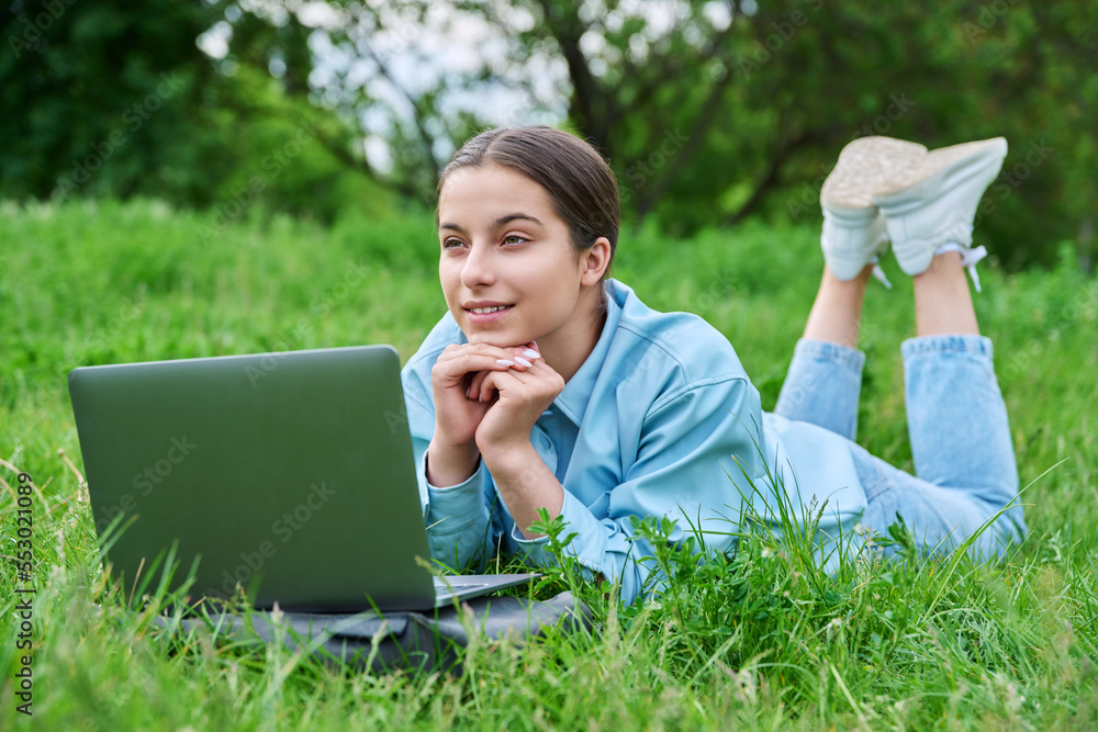 Teenage female student lying on the grass using a laptop Teenage female student lying on the grass using a laptop